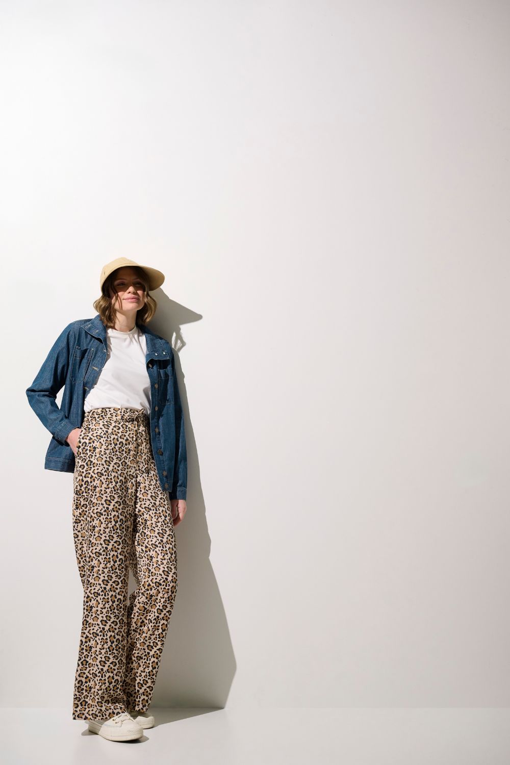 Femme portant un pantalon anti-UV - Positano, large à motifs léopard, avec un t-shirt léger, protection solaire.