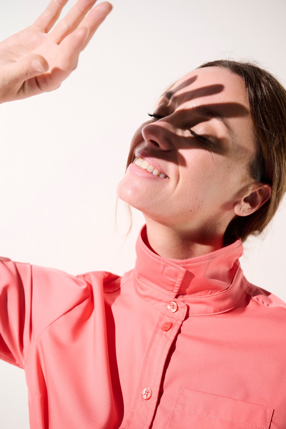Femme souriante en chemise anti-UV rose, UPF 50+, idéale pour la protection solaire élégante.