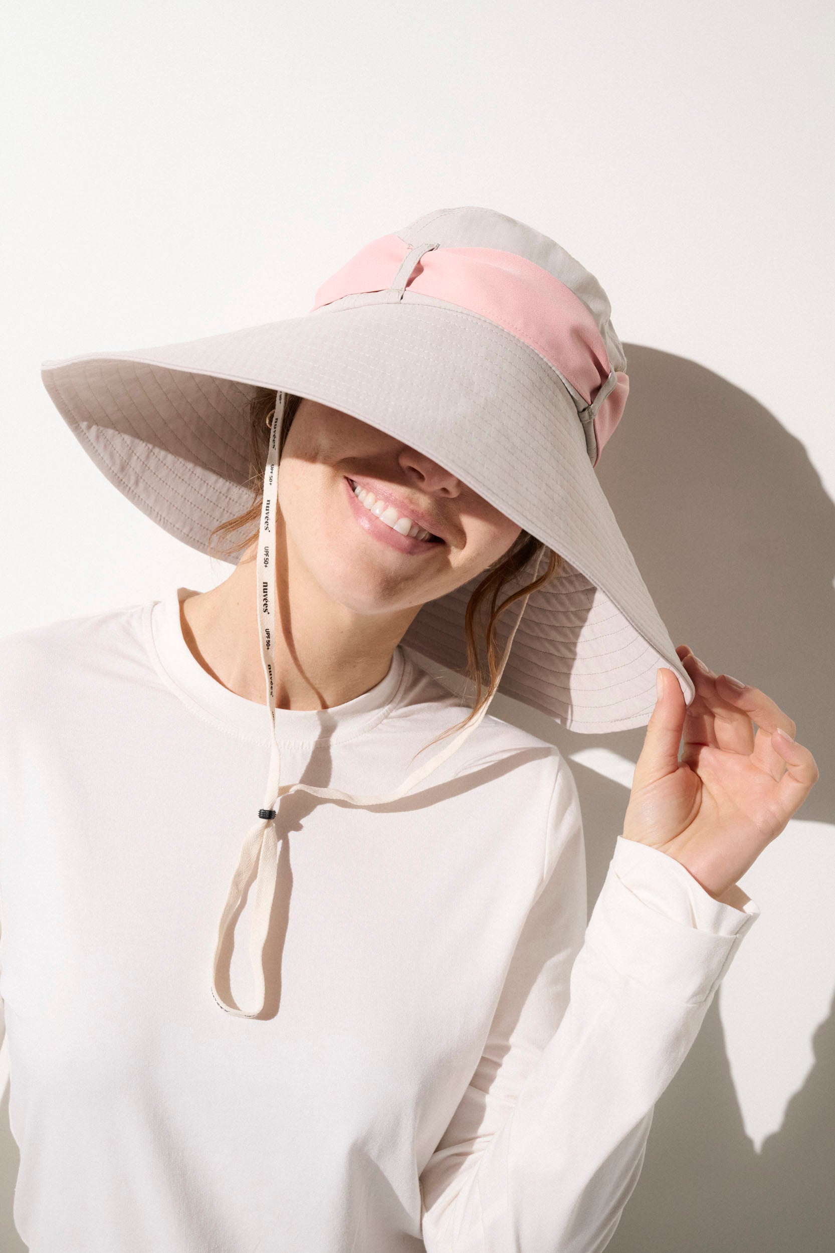 Chapeau anti-UV beige avec bande rose, pour femmes, offrant protection solaire UPF50+ lors d'activités extérieures.
