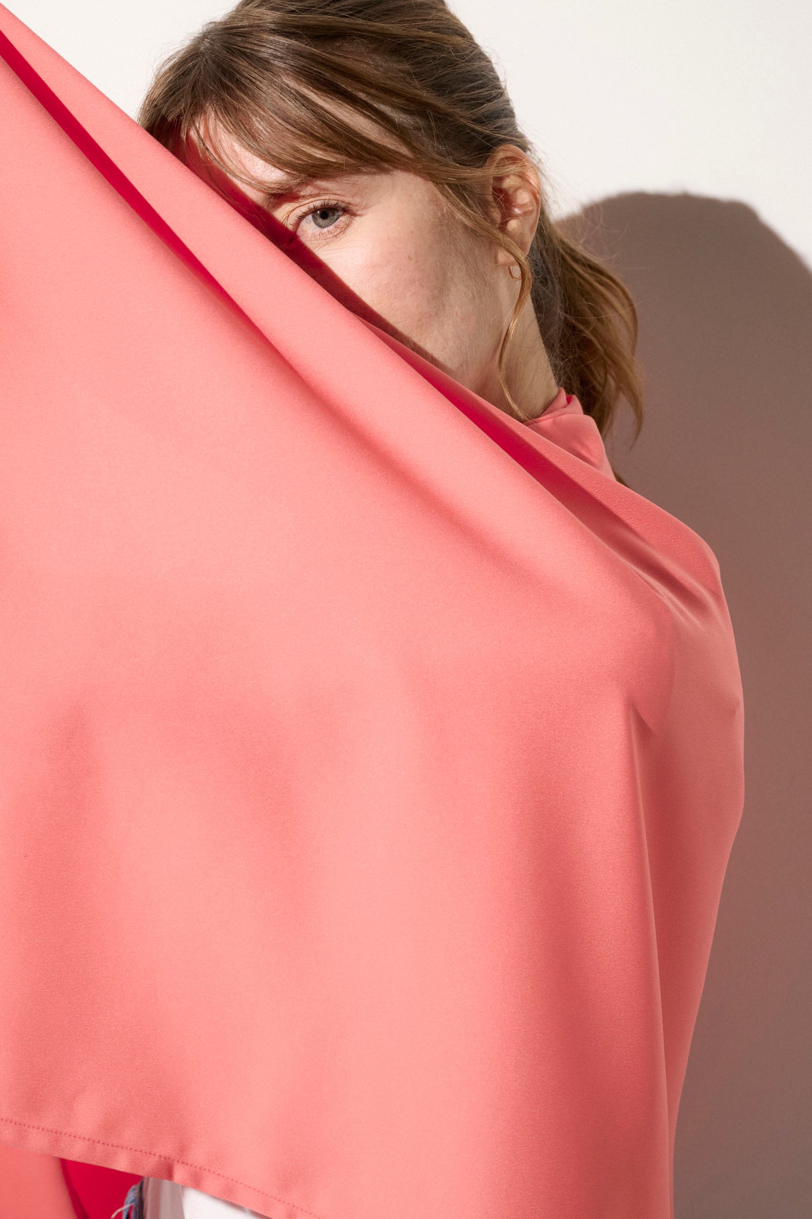 Femme portant une étole anti-UV rose, légère et élégante, offrant une protection solaire UPF50+.