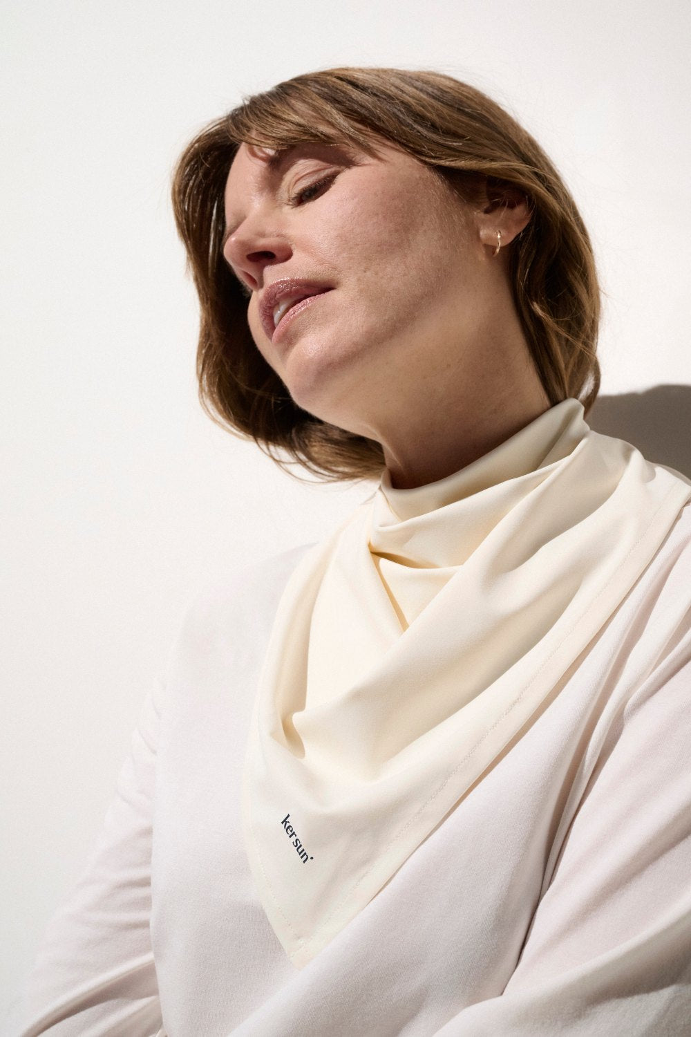 Femme portant un bandana anti-UV blanc, UPF 50+, élégant pour une protection solaire estivale.