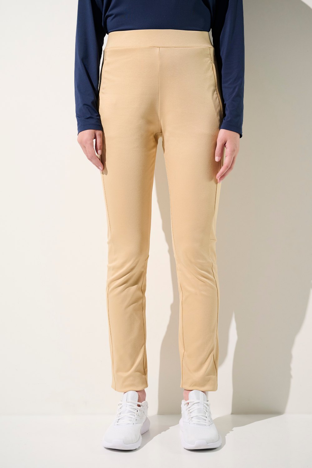 Pantalon anti-UV beige pour femme, léger et confortable, offrant une protection solaire UPF 50+, porté avec des chaussures blanches.
