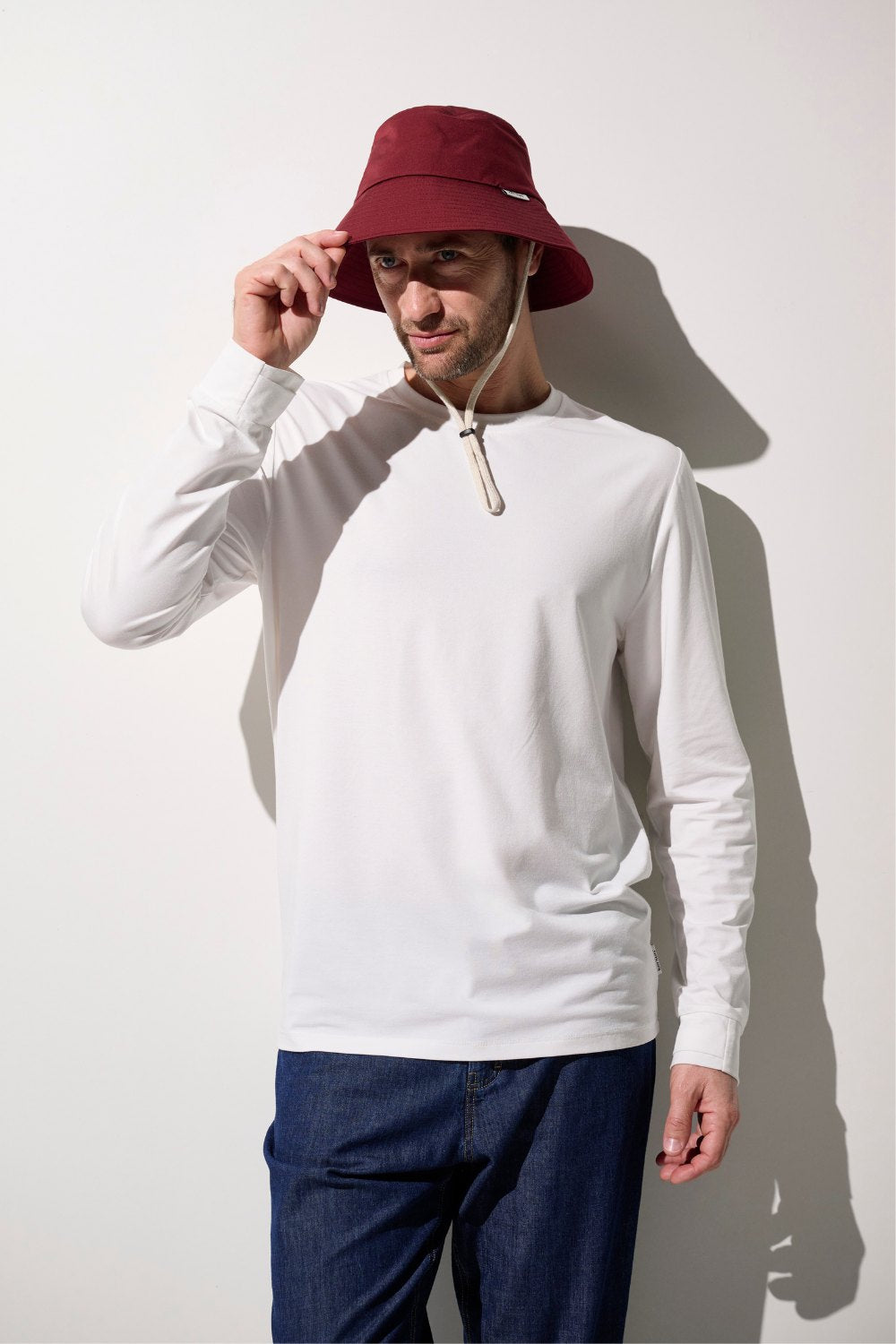 Homme portant un bob anti-UV - Faro couleur bordeaux et t-shirt anti-UV blanc, offrant protection solaire UPF 50+.