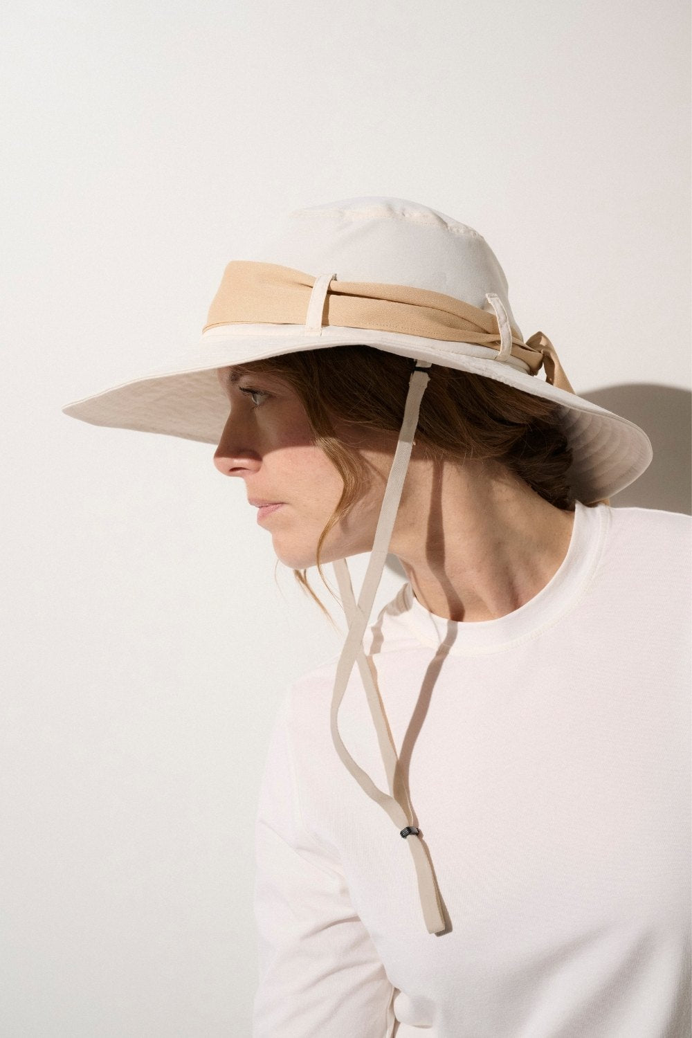 Chapeau anti-UV beige pour femme, léger et élégant, offrant une protection solaire UPF 50+ lors d'activités extérieures.