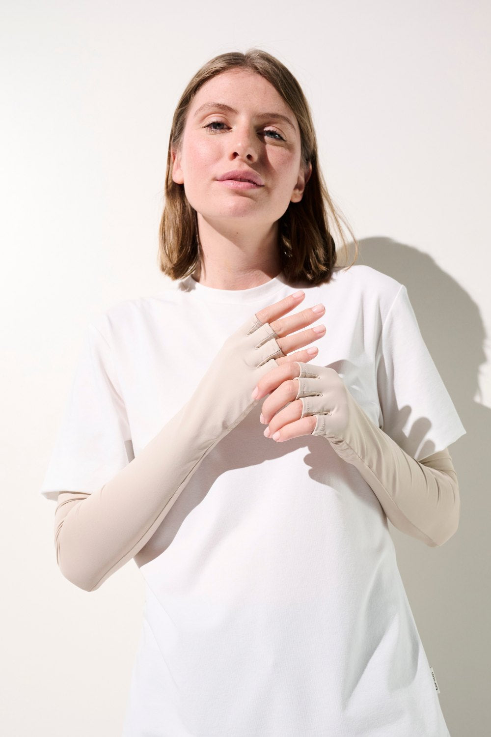 Femme portant un t-shirt blanc et des mitaines anti-UV UPF 50+, idéales pour une protection solaire quotidienne.