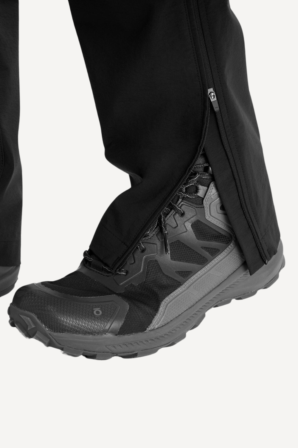 Pantalon anti-UV noir avec fermeture éclair, porté avec des chaussures de randonnée robustes pour activités en extérieur.