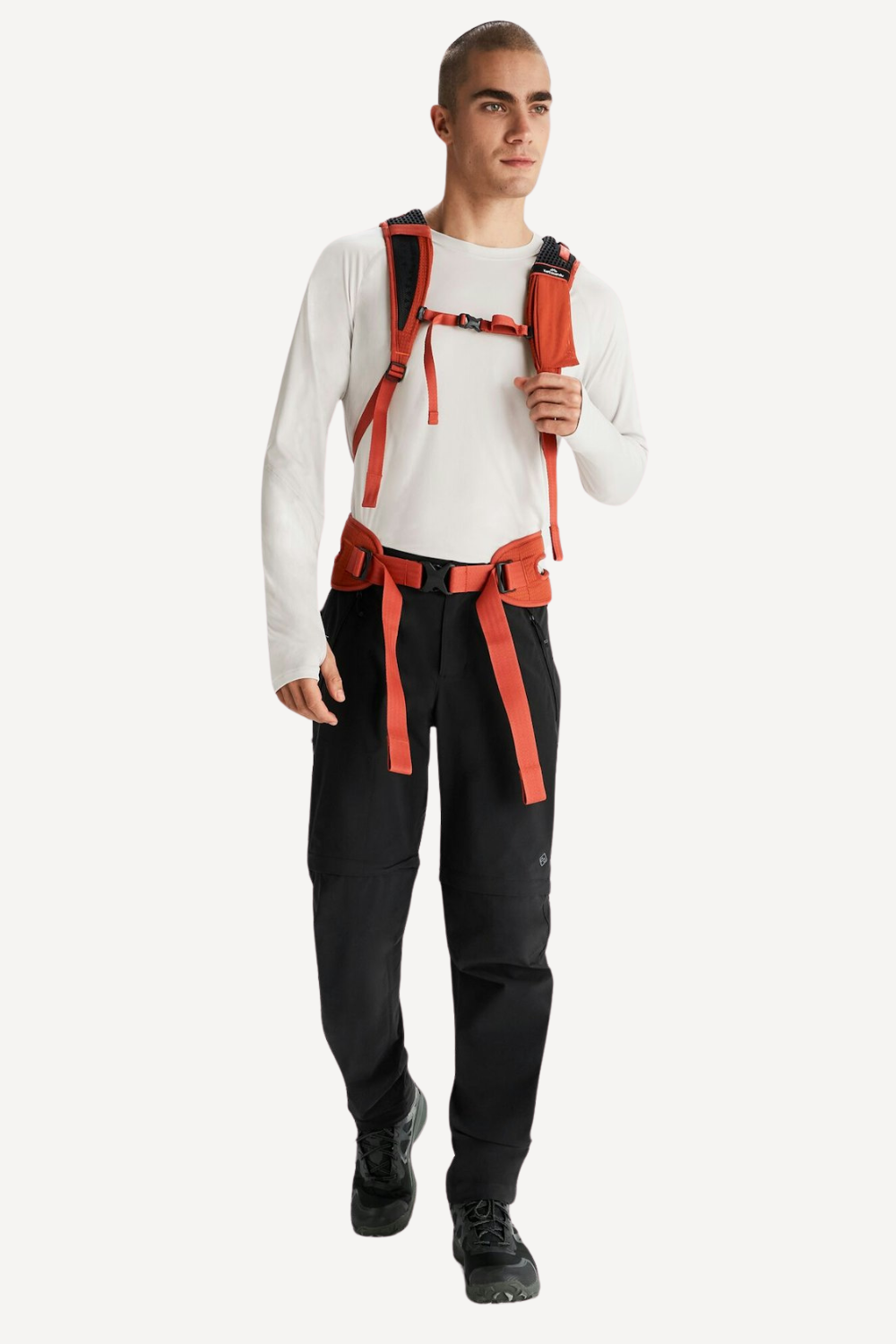 Homme portant un pantalon anti-UV noir et un sweat à manches longues, équipé d'un harnais de randonnée.