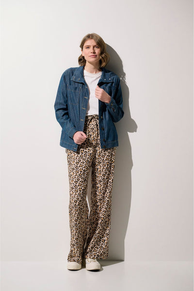 Femme portant un pantalon anti-UV - Positano à motifs léopard et une veste en jean, élégance décontractée.