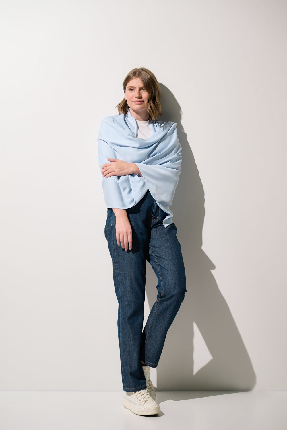 Étole anti-UV - Positano en bleu clair portée par une femme, offrant une élégante protection solaire UPF 50+.