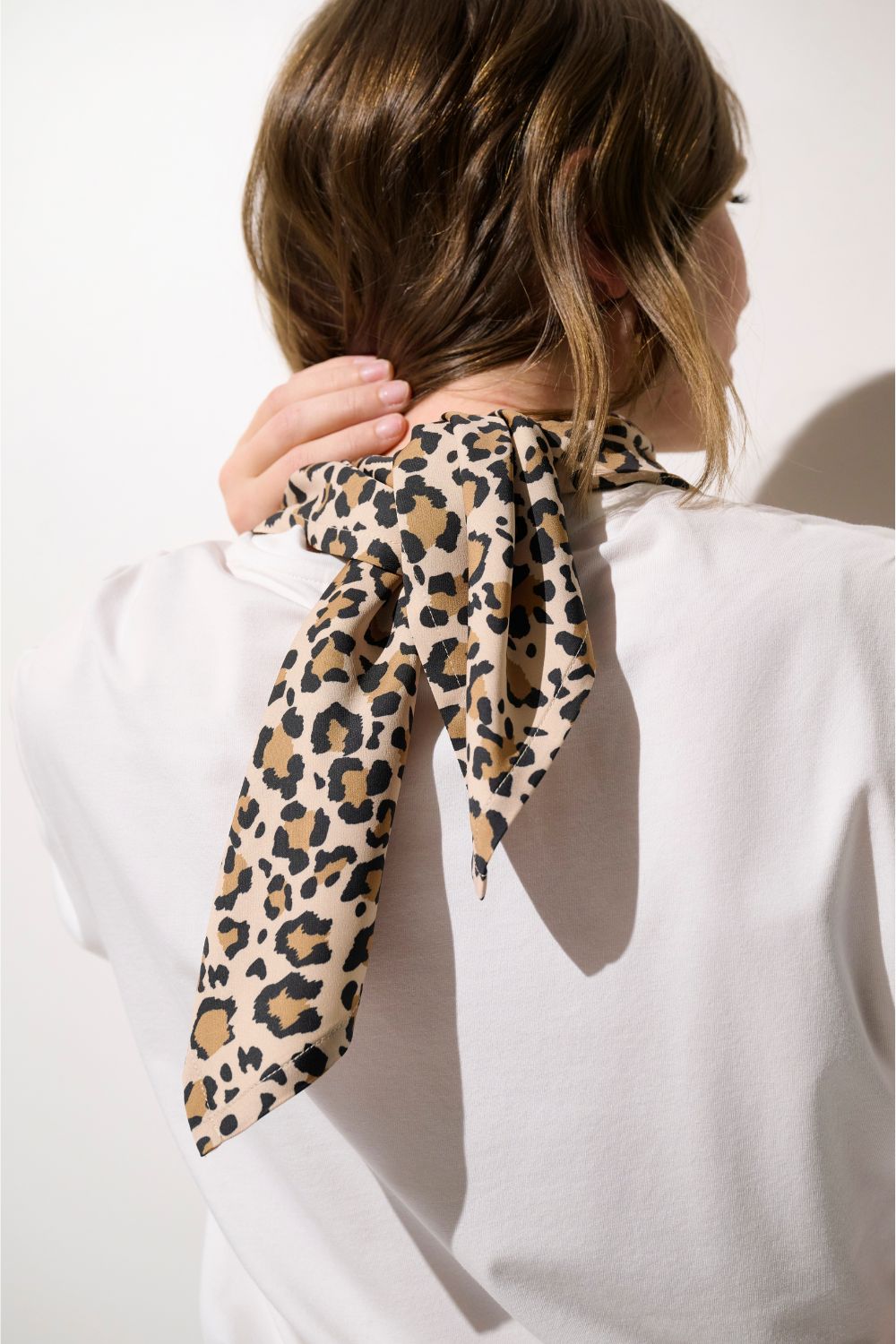 Foulard anti-UV - Positano pour femme, motif léopard, noué autour du cou pour une élégance estivale.
