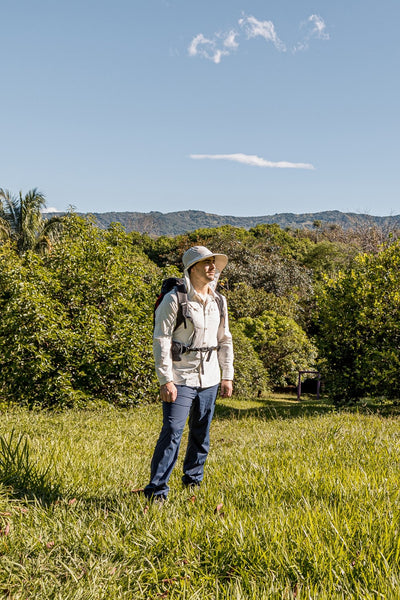 Femme portant un chapeau anti-UV Mojave, UPF 50+, en randonnée dans la nature verdoyante.