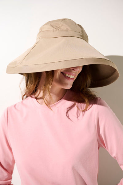 Chapeau anti-UV - Faro beige UPF 50+, femme souriante portant un chapeau à large bord pour activités extérieures.