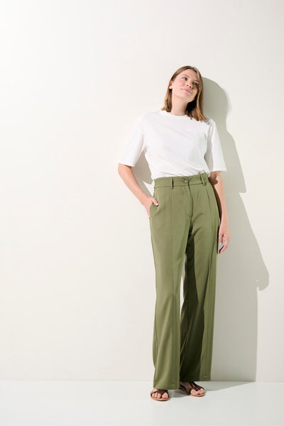 Femme portant un t-shirt blanc et un pantalon vert décontracté, élégant pour un look moderne.