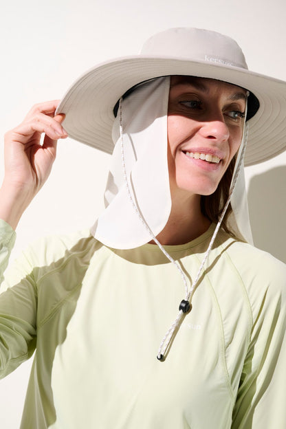 Femme souriante portant un cache-nuque anti-UV - Gobi et chapeau, idéal pour une protection solaire UPF 50+.