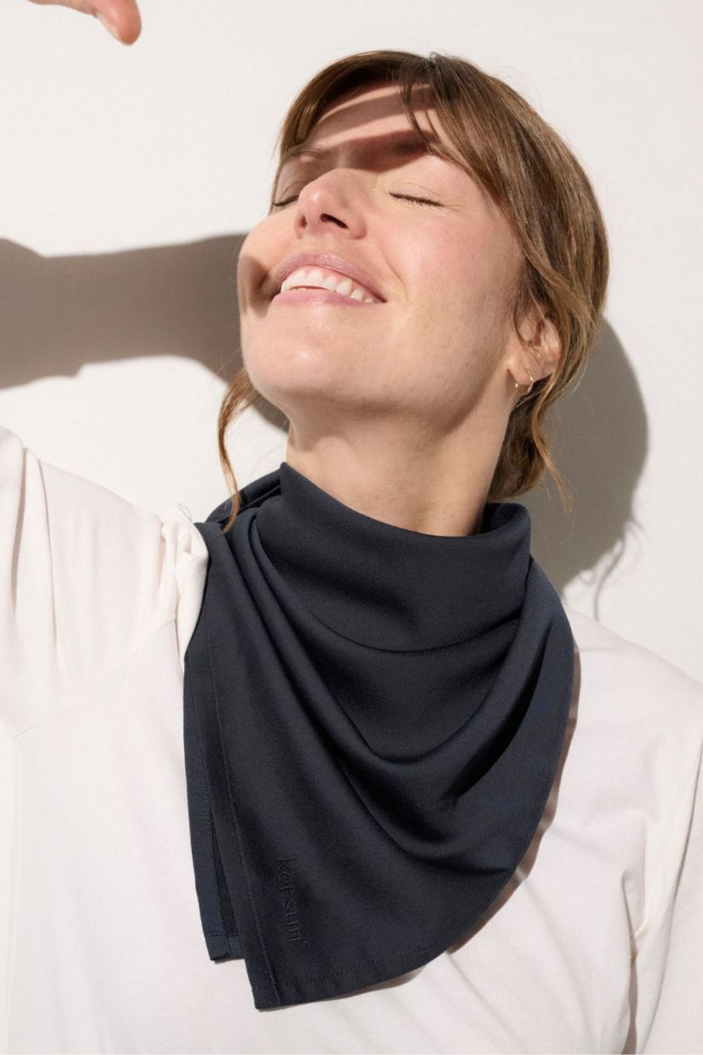 Foulard anti-UV - Positano en noir, porté par une femme, offrant une protection solaire UPF 50+ élégante.