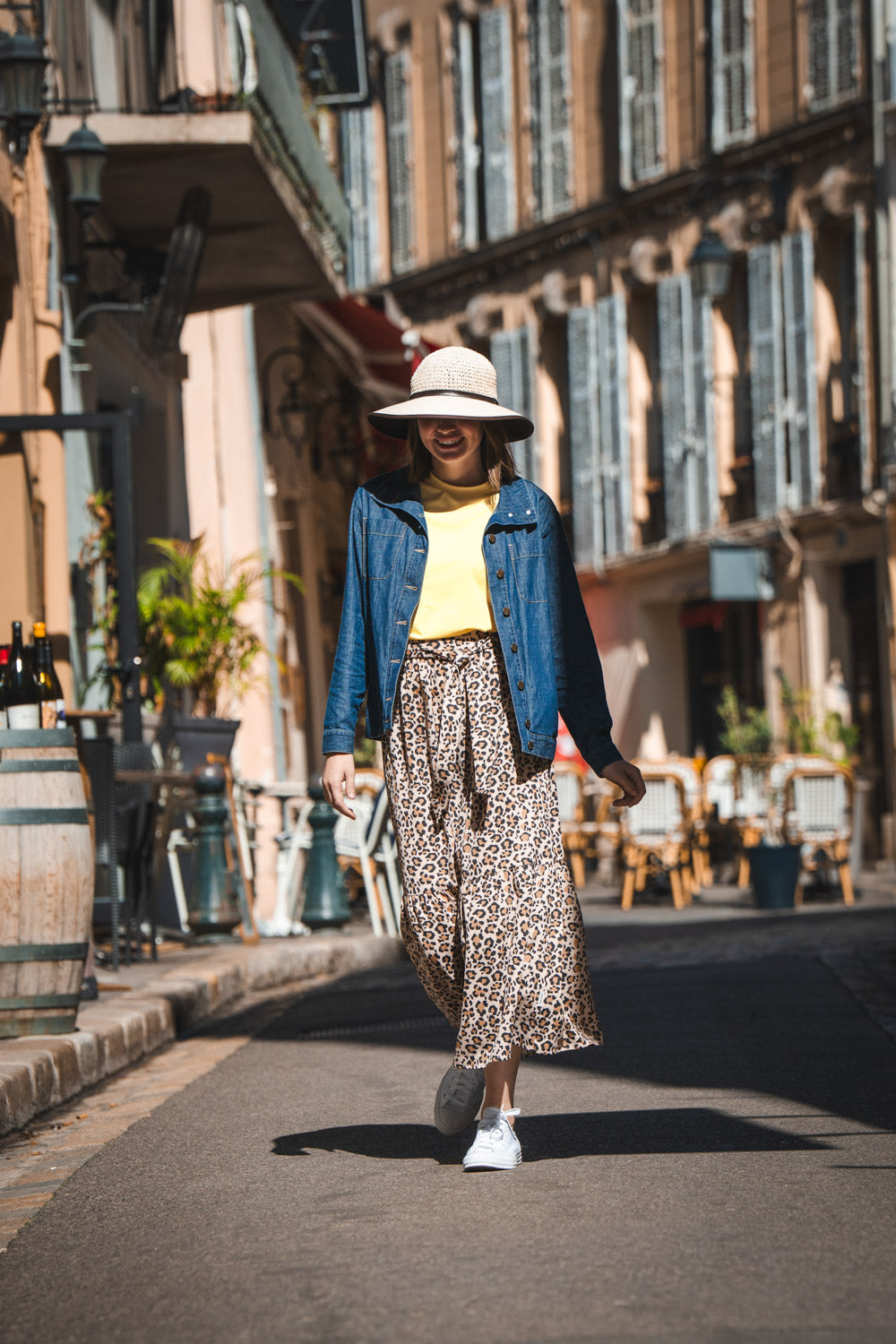 Jupe anti-UV - Positano à motifs léopard, portée par une femme dans une rue ensoleillée, idéale pour la protection solaire.